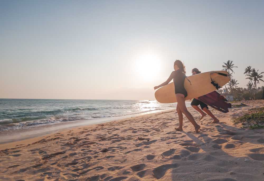 two people with surfboards running toward ocean