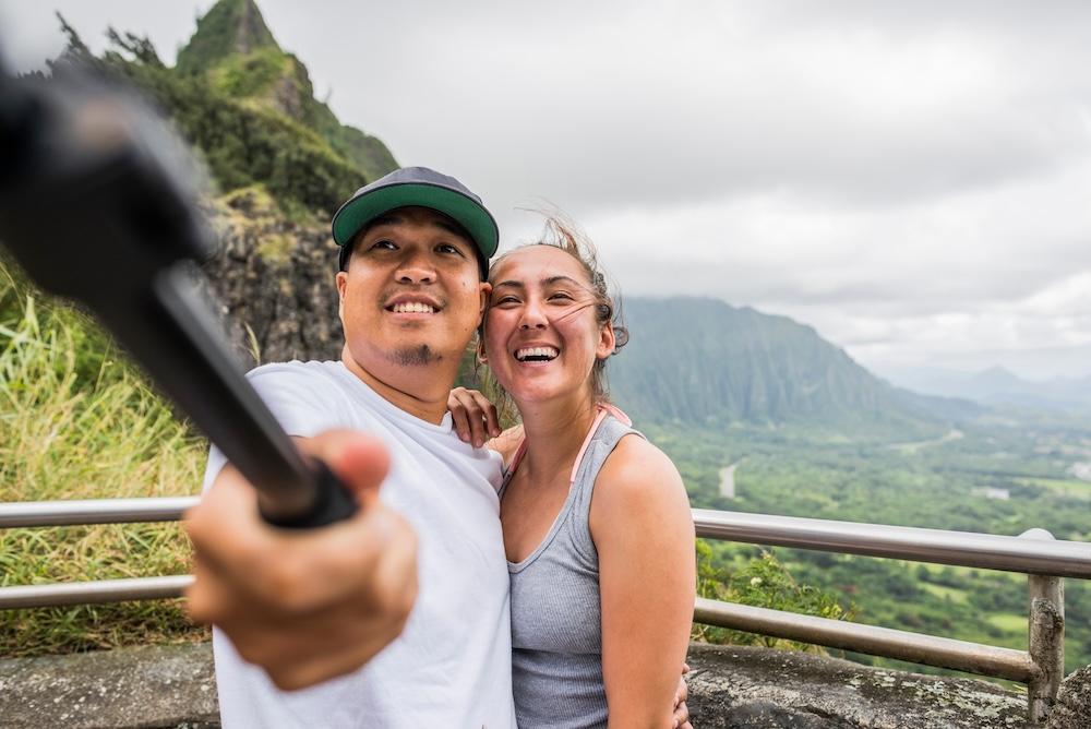 Young couple pointing from viewing platform, Nuuanu Pali, Oahu, Hawaii, USA.